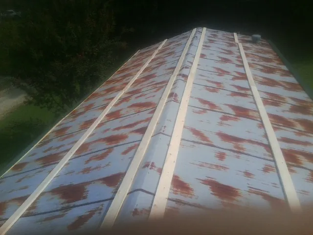 Rusted metal roof panels with new wood purlins before replacement — Storm Damage Roof Repair in East Wakefield by Roofing Brothers