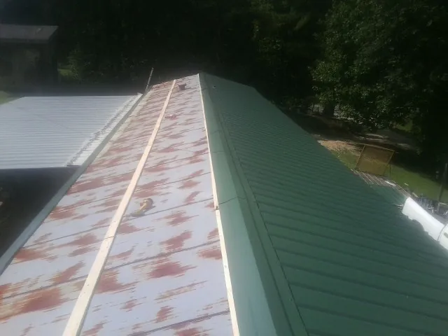 Old rusted panels beside newly installed green metal roofing — Wind Damage Roof Repair by Roofing Brothers in East Wakefield