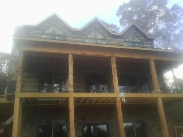 Dormers and porch framing on a large log home under construction — Roof Coating work by our crew in East Wakefield