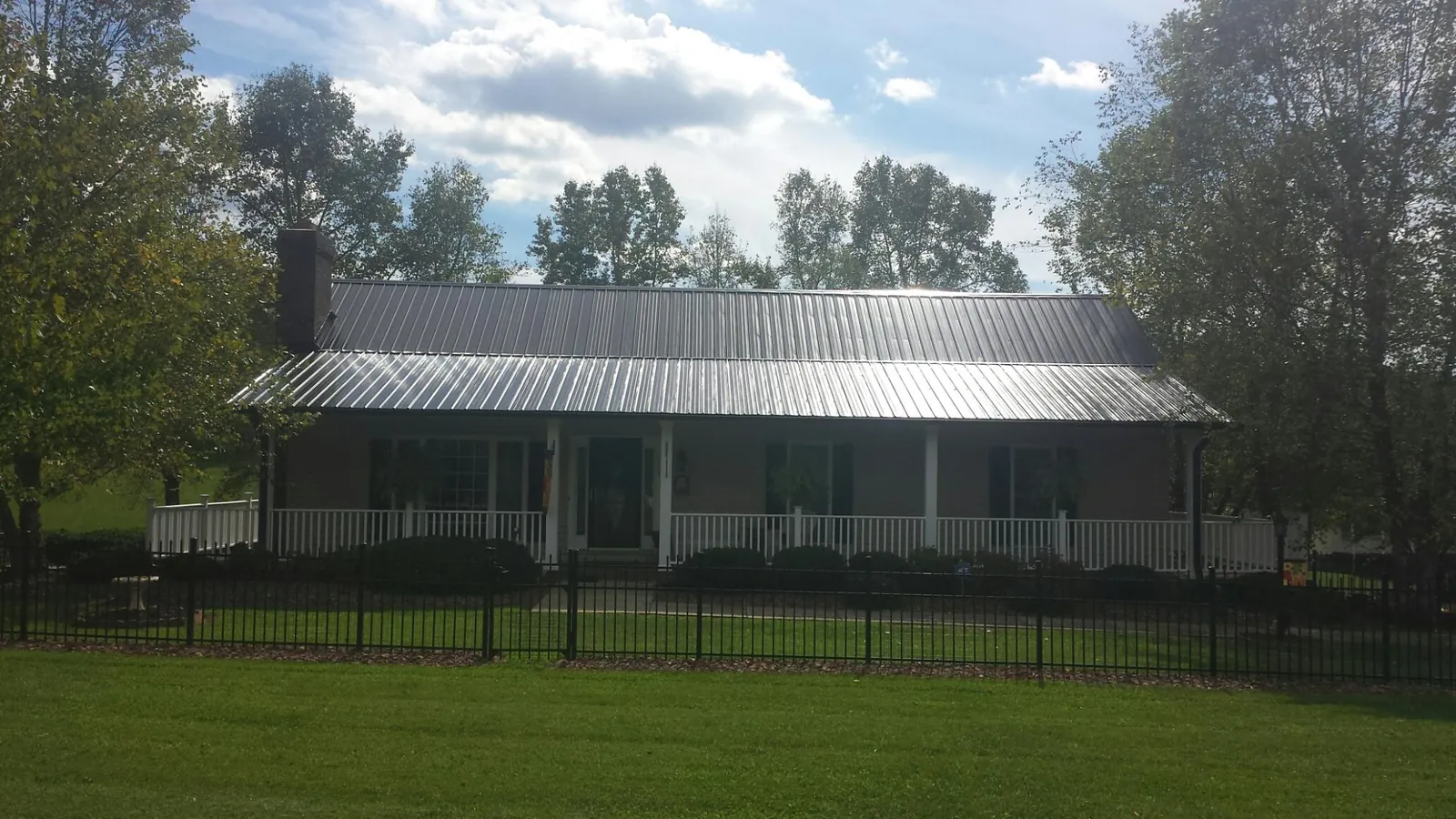 Gray metal roof on a brick ranch with a full width front porch — Gutter Guard Installation work by our crew in East Wakefield