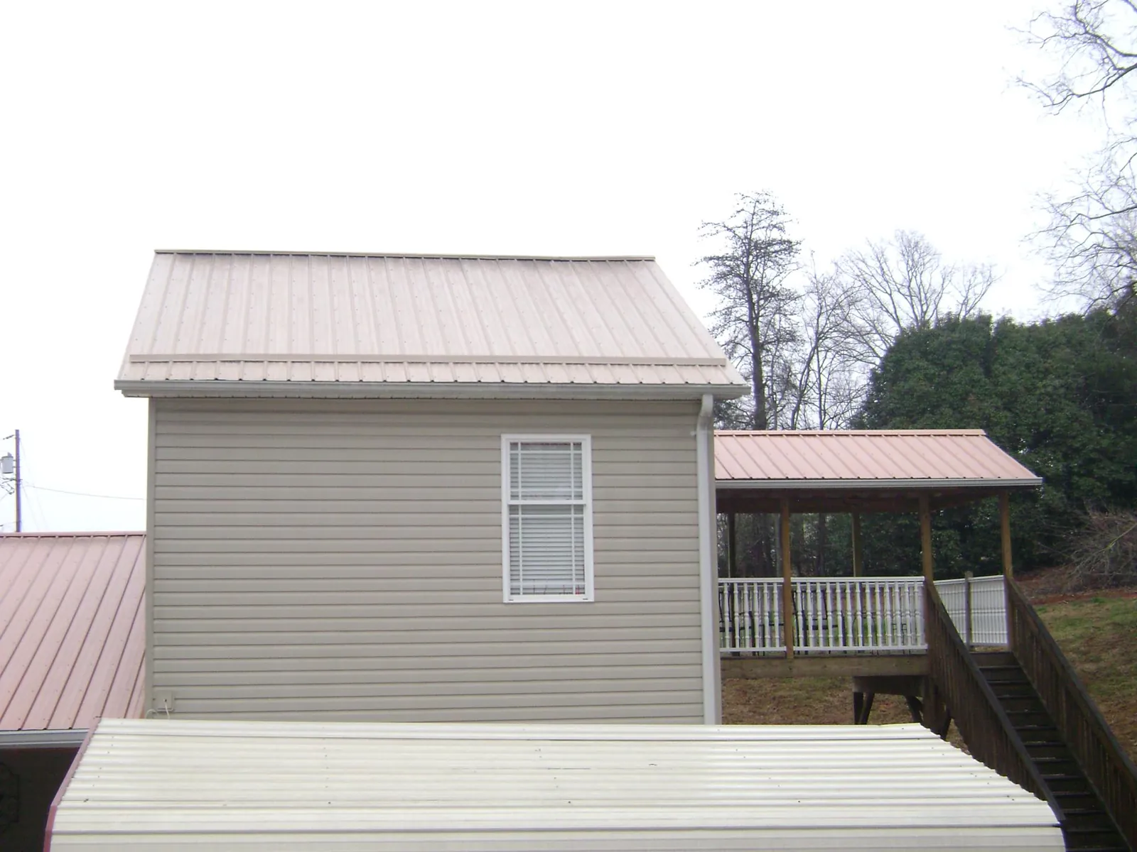 Tan metal roofs on a two story addition and attached porch, from a Roof Replacement job in East Wakefield